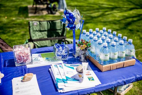 Water bottles, pinwheels, mints, and fliers sit on top of a blue covered table