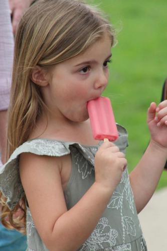 A young girl eats a popsicle