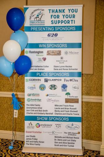 Blue and white balloons next to a banner with the names or logos for the event sponsors