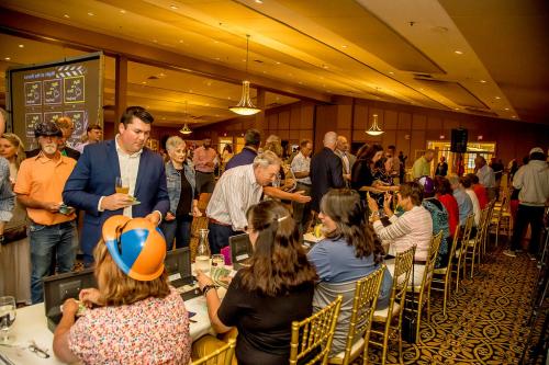 People placing bets at the betting tables with other people seated on the other side of the table in gold chairs taking bets