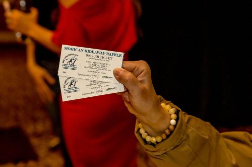A close up of a hand holding two raffle tickets