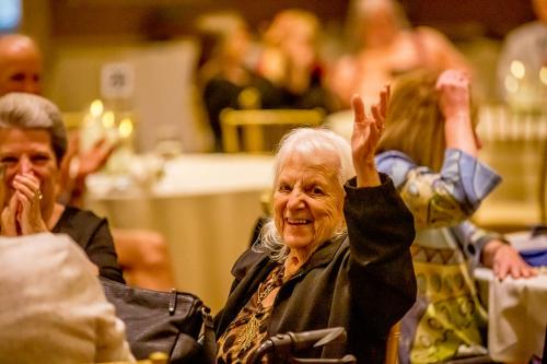 A woman in a black jacket holding up her hand in acknowledgement
